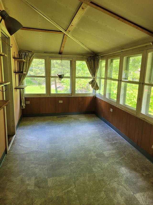 unfurnished sunroom featuring tile patterned floors, wooden walls, and vaulted ceiling