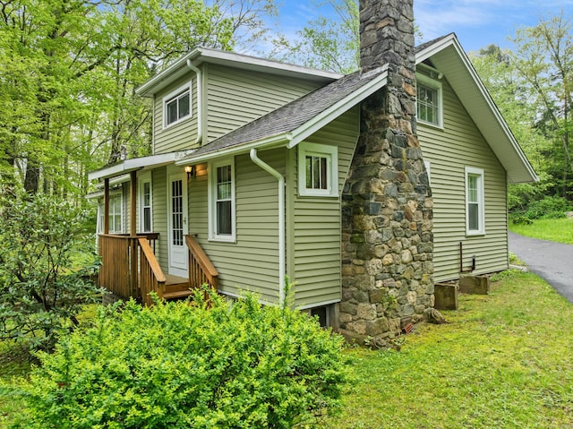 back of house with a chimney, a shingled roof, and a yard