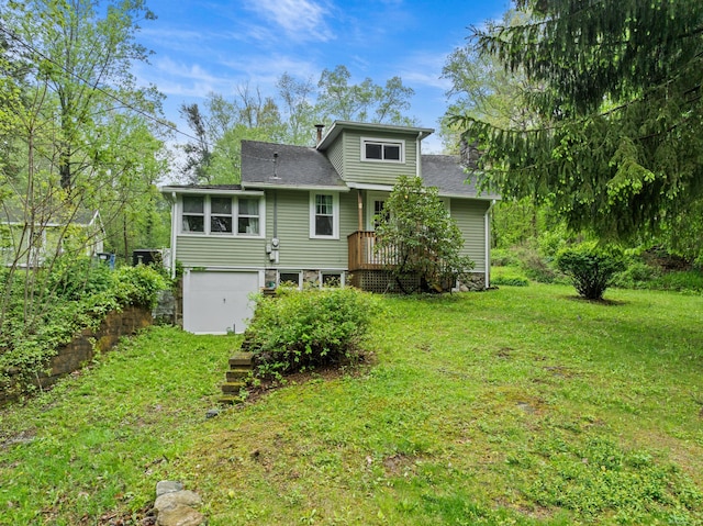 back of house featuring a yard, a deck, and roof with shingles