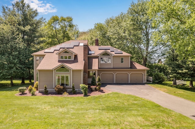 17 Pasture Ln, Glastonbury, CT 06073 - view of front facade featuring asphalt driveway, solar panels, a front yard, a chimney, and a garage