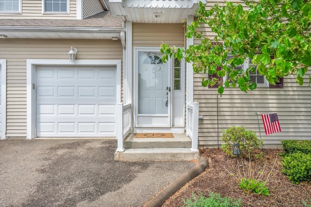 view of exterior entry with a shingled roof and a garage