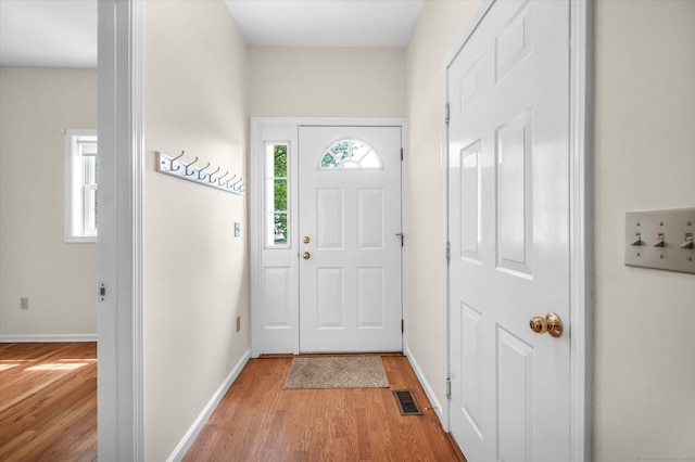 doorway featuring light wood finished floors and baseboards