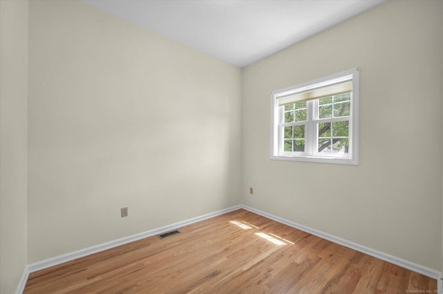 spare room with baseboards and light wood-type flooring