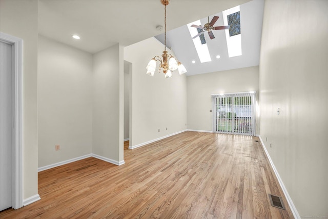 empty room with a skylight, a chandelier, light wood-style flooring, high vaulted ceiling, and baseboards