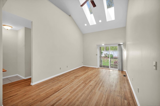 unfurnished room featuring high vaulted ceiling, a skylight, wood finished floors, baseboards, and recessed lighting