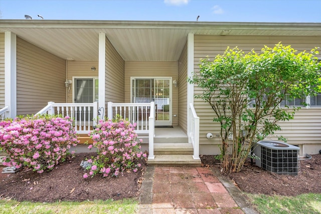 view of exterior entry featuring central AC and a porch
