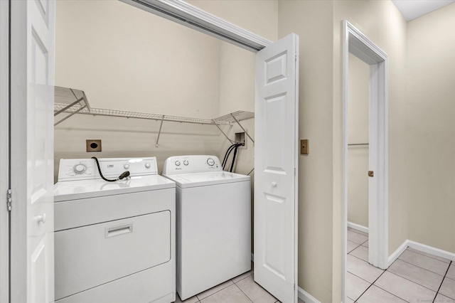 washroom with separate washer and dryer, light tile patterned flooring, and baseboards