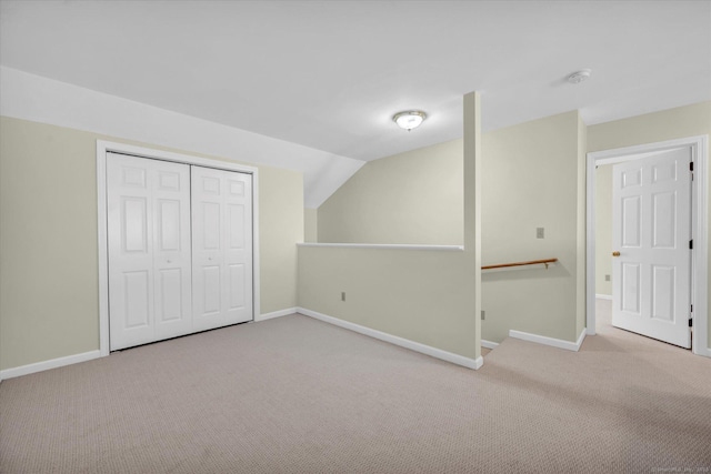 unfurnished bedroom featuring carpet flooring, baseboards, lofted ceiling, and a closet