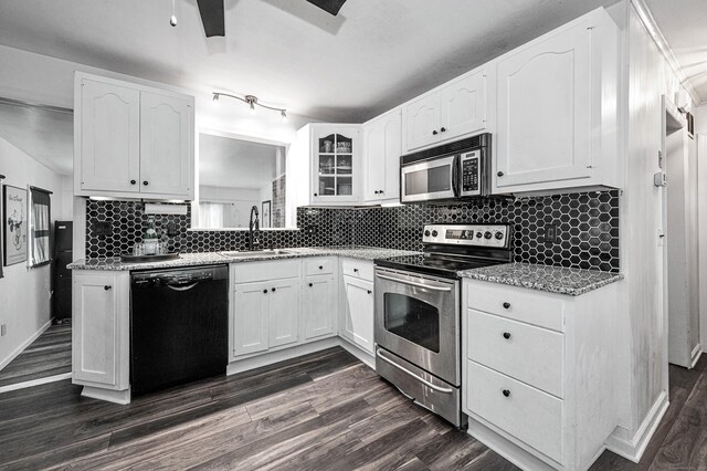 kitchen with dark wood-style flooring, stainless steel appliances, white cabinetry, and a sink