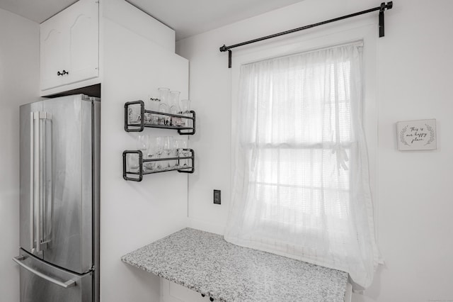 interior space with white cabinets, light stone countertops, and high quality fridge