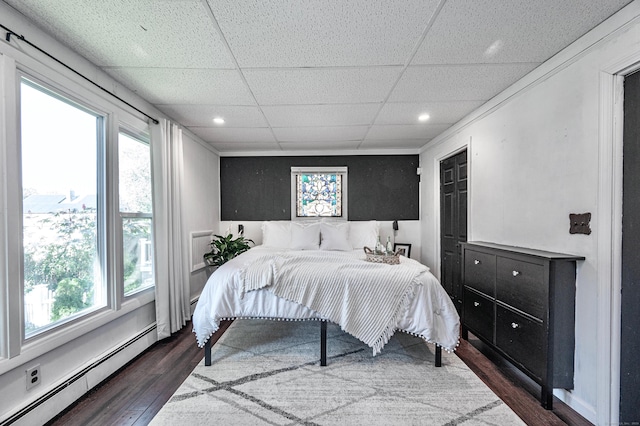 bedroom with recessed lighting, a drop ceiling, dark wood-style floors, and a baseboard radiator