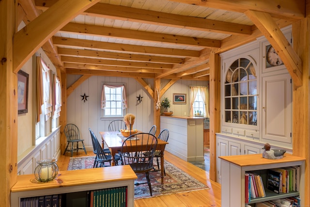 dining room featuring light wood-style floors, wooden ceiling, and lofted ceiling with beams