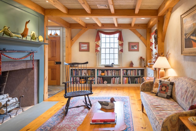living area featuring beamed ceiling, visible vents, and wood-type flooring