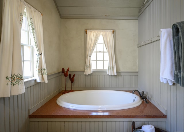 full bathroom with wainscoting, a garden tub, and plenty of natural light