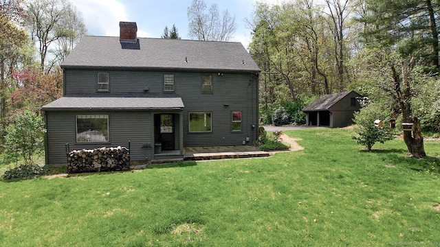 back of house featuring an outdoor structure, a chimney, and a lawn