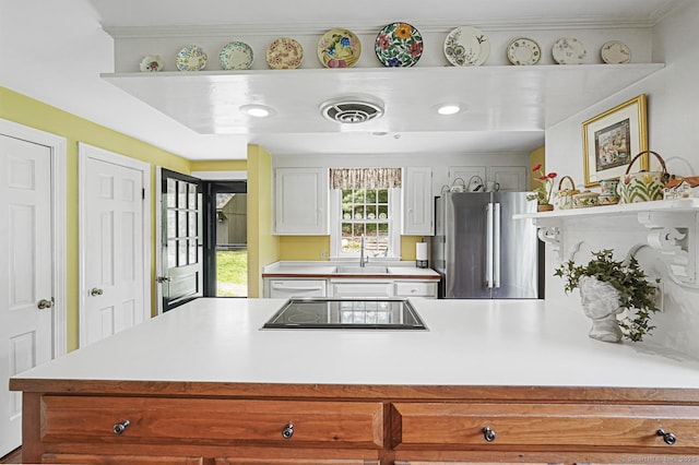 kitchen featuring freestanding refrigerator, dishwasher, a peninsula, black electric cooktop, and light countertops
