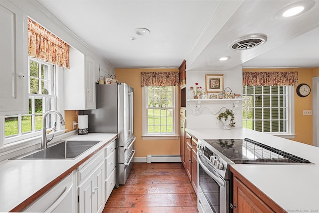 kitchen with a wealth of natural light, appliances with stainless steel finishes, a baseboard radiator, and a sink
