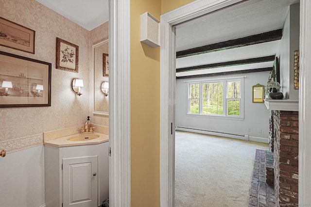 bathroom featuring wallpapered walls, a baseboard heating unit, baseboards, vanity, and a fireplace