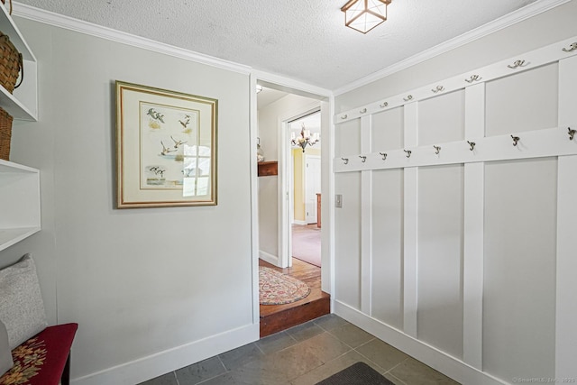 mudroom with dark tile patterned flooring, crown molding, a textured ceiling, and baseboards