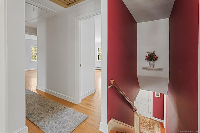 hall featuring attic access, wood finished floors, an upstairs landing, and baseboards