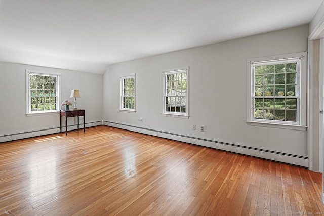 spare room with lofted ceiling, light wood-style flooring, plenty of natural light, and a baseboard heating unit