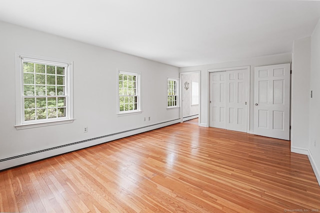unfurnished bedroom featuring light wood-type flooring, baseboards, and a baseboard radiator