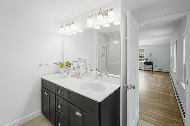 bathroom with a shower with shower door, wood finished floors, baseboard heating, and a sink