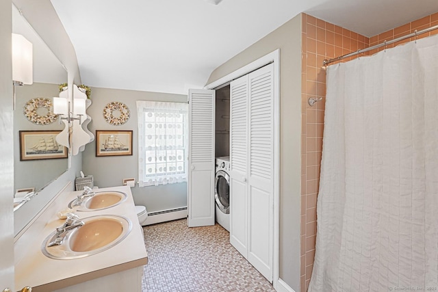 full bathroom with washer / dryer, a tile shower, a baseboard heating unit, and a sink