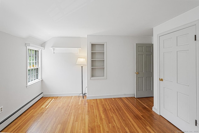 unfurnished room with built in features, light wood-style flooring, baseboards, and a baseboard heating unit