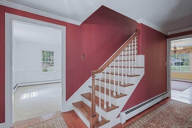 stairs with ornamental molding, a baseboard radiator, baseboards, and wood finished floors