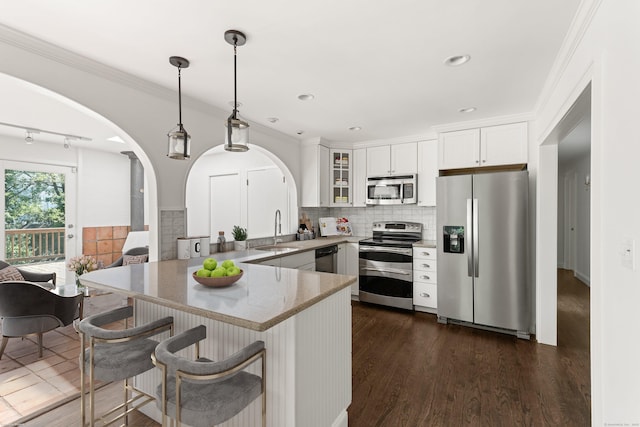 16 Wakerobin Rd, Norwalk, CT 06851 - kitchen with stainless steel appliances, a sink, arched walkways, a peninsula, and glass insert cabinets