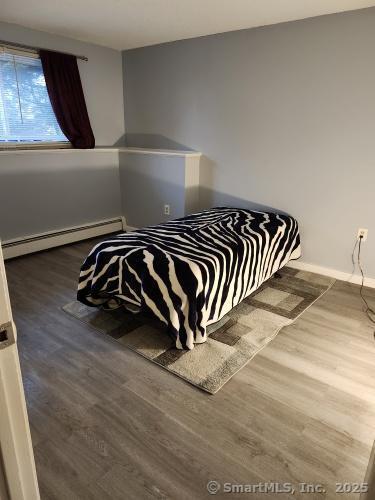 58 Evergreene Unit 58, Wallingford, CT 06492 - bedroom featuring baseboard heating, wood finished floors, and baseboards