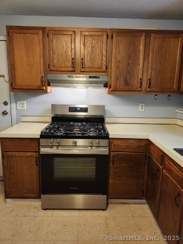 58 Evergreene Unit 58, Wallingford, CT 06492 - kitchen with gas stove, under cabinet range hood, light countertops, and brown cabinetry