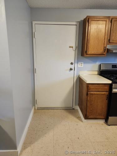 58 Evergreene Unit 58, Wallingford, CT 06492 - kitchen with gas range, under cabinet range hood, baseboards, light countertops, and brown cabinetry