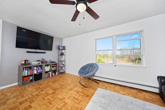 sitting room with baseboards, ceiling fan, and baseboard heating