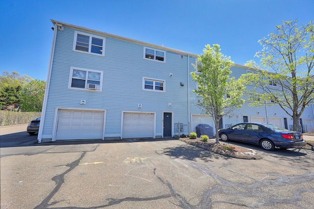 view of front of house featuring an attached garage, aphalt driveway, and cooling unit