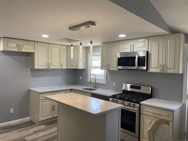 kitchen with recessed lighting, light countertops, a sink, light wood-style flooring, and appliances with stainless steel finishes
