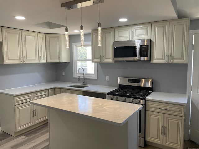 kitchen with a kitchen island, a sink, light countertops, light wood finished floors, and stainless steel appliances