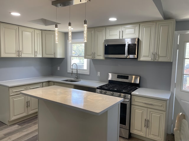 kitchen with a sink, light wood-style floors, light countertops, stainless steel appliances, and a kitchen island