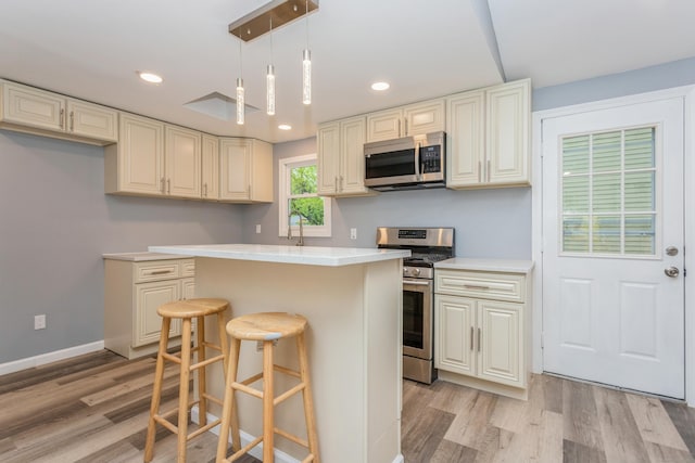 75 Edwards St, Bridgeport, CT 06606 - kitchen with stainless steel appliances, light wood-style flooring, a center island, a kitchen breakfast bar, and light countertops