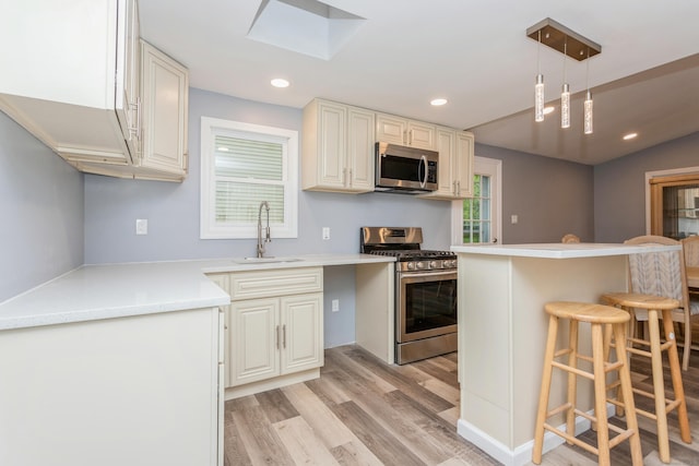 75 Edwards St, Bridgeport, CT 06606 - kitchen featuring appliances with stainless steel finishes, a sink, a kitchen breakfast bar, light wood-style flooring, and a skylight