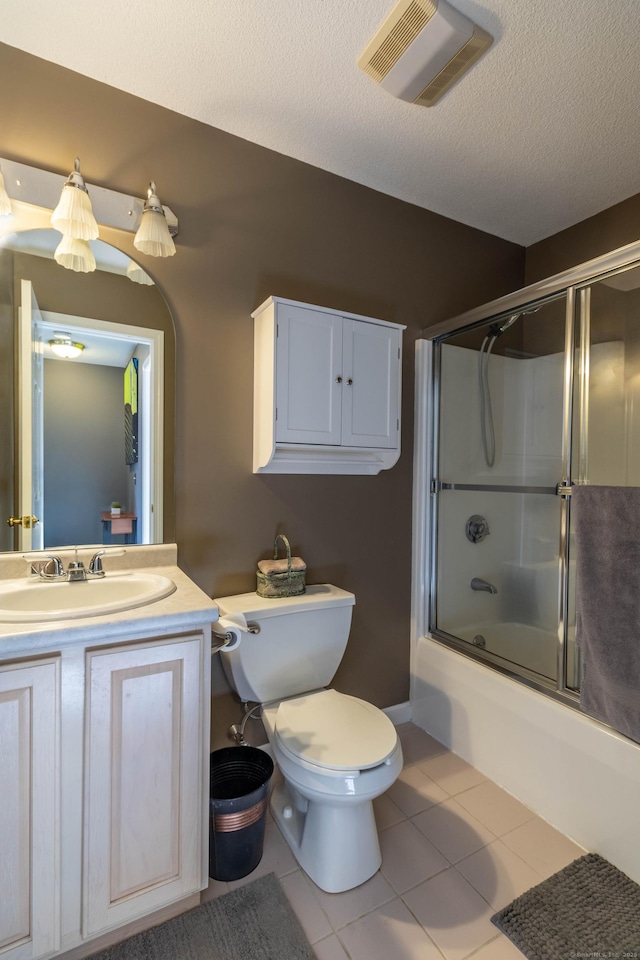 bathroom featuring visible vents, vanity, toilet, tile patterned floors, and combined bath / shower with glass door