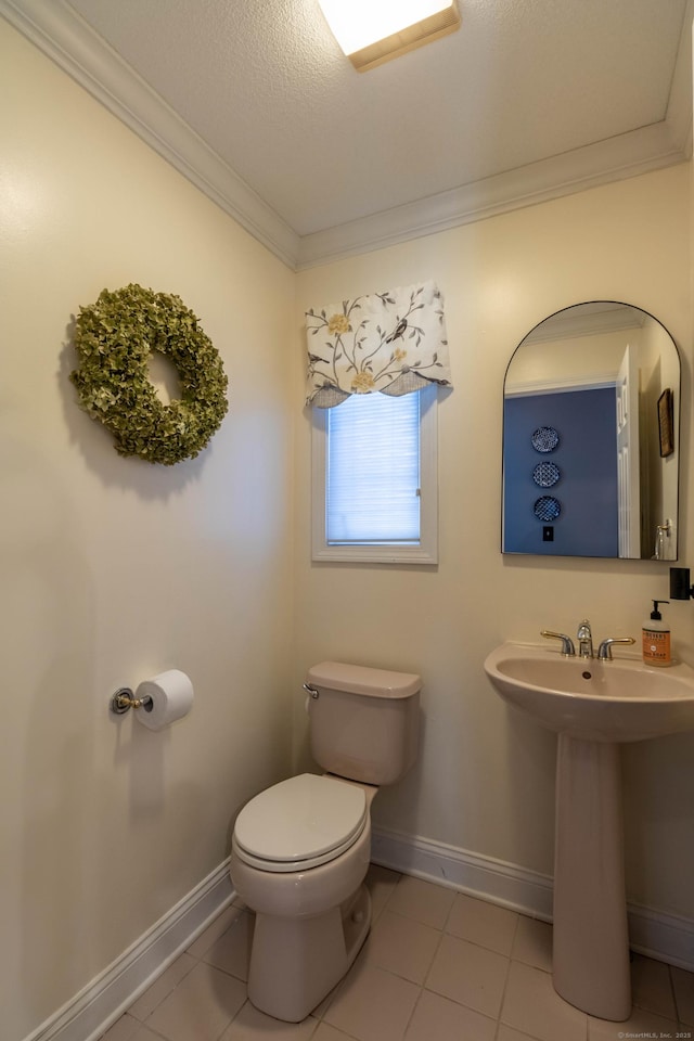 half bathroom featuring baseboards, ornamental molding, tile patterned flooring, and toilet