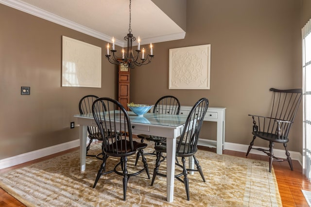 dining area featuring crown molding, baseboards, a notable chandelier, and wood finished floors