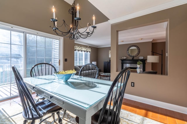 dining room featuring an inviting chandelier, baseboards, crown molding, and wood finished floors