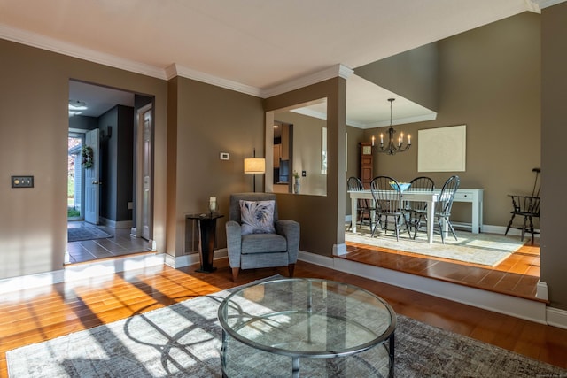 living room with crown molding, baseboards, a chandelier, and wood finished floors