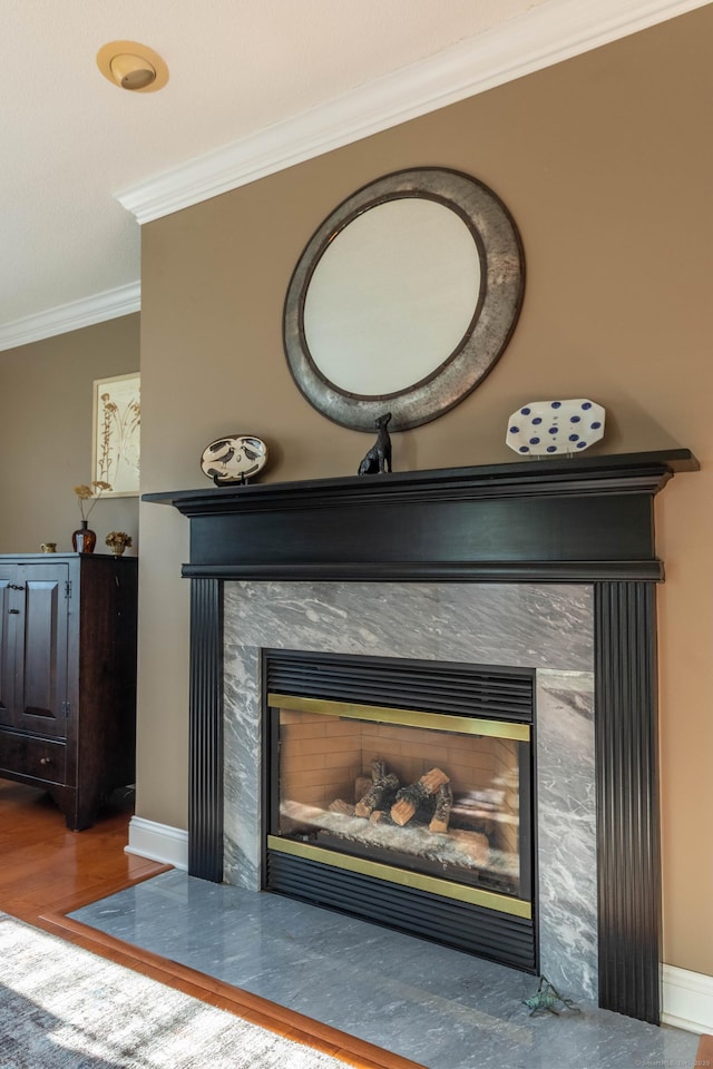 details with crown molding, baseboards, a fireplace with flush hearth, and wood finished floors