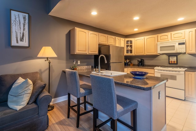 kitchen with a sink, white appliances, a breakfast bar area, a peninsula, and glass insert cabinets