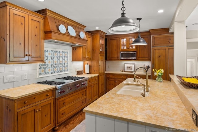 kitchen featuring a sink, stainless steel appliances, brown cabinets, hanging light fixtures, and recessed lighting