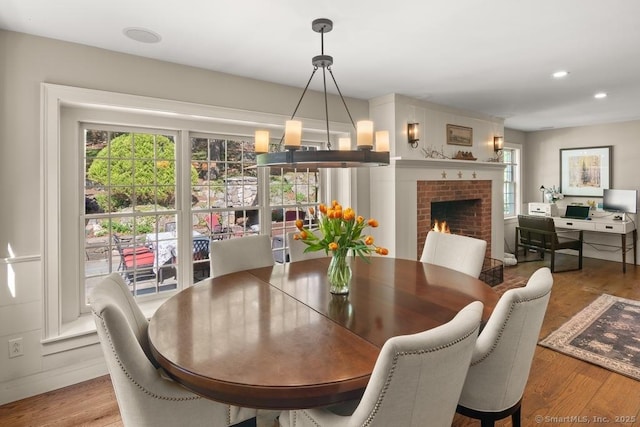 dining space with wood finished floors, a brick fireplace, and recessed lighting